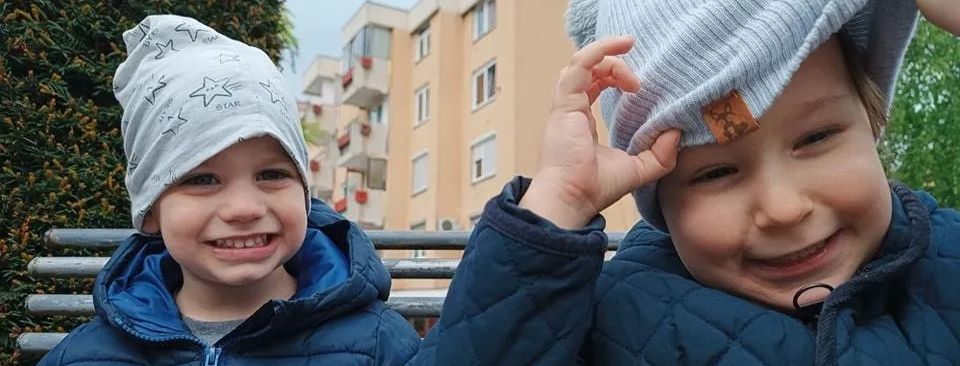 Dva dječaka Vrtića Ću-Ću u zimskim kapama ispred zgrada na Alipašinom Polju